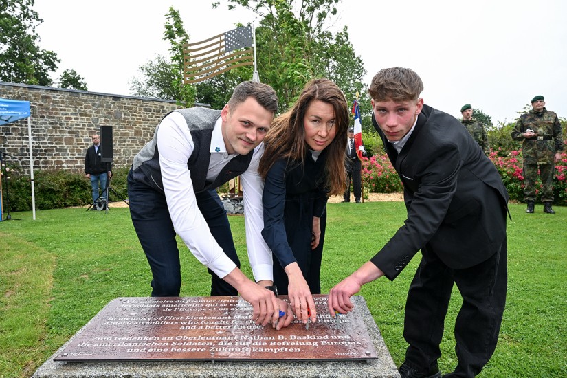 Auszubildende und dual Studierende drehen stilisierte Blüten aus Stahl in die Informationstafel zum Gedenkzeichen ein.