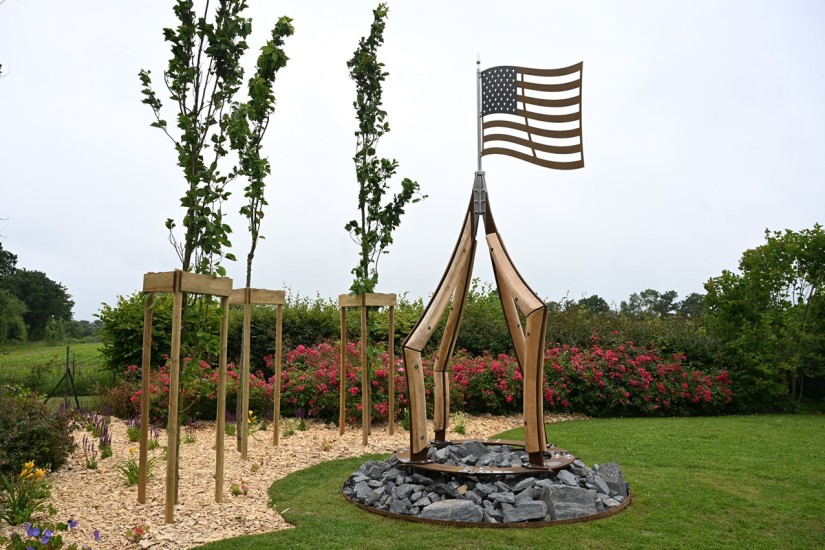 Gedenkzeichen in Form einer stilisierten amerikanischen Flagge auf abstrahierten Beinen marschierender Soldaten.